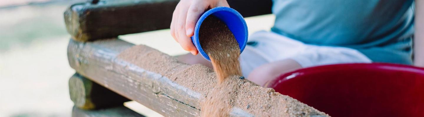 Kind spielt draußen mit Sand