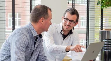 Foto van 2 mannen die overleggen over de software van Payt achter een laptop
