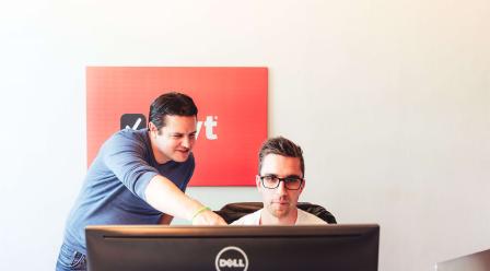 Foto van twee mannen die werken achter een computer
