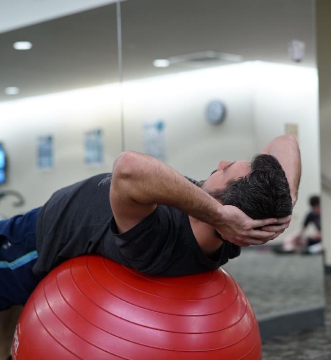 Foto van een patient die oefeningen doet op een bal bij de fysio